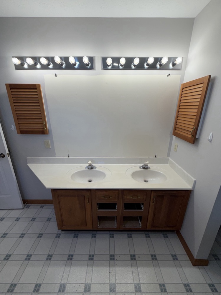 Before: dated oak double vanity with bulb light bars