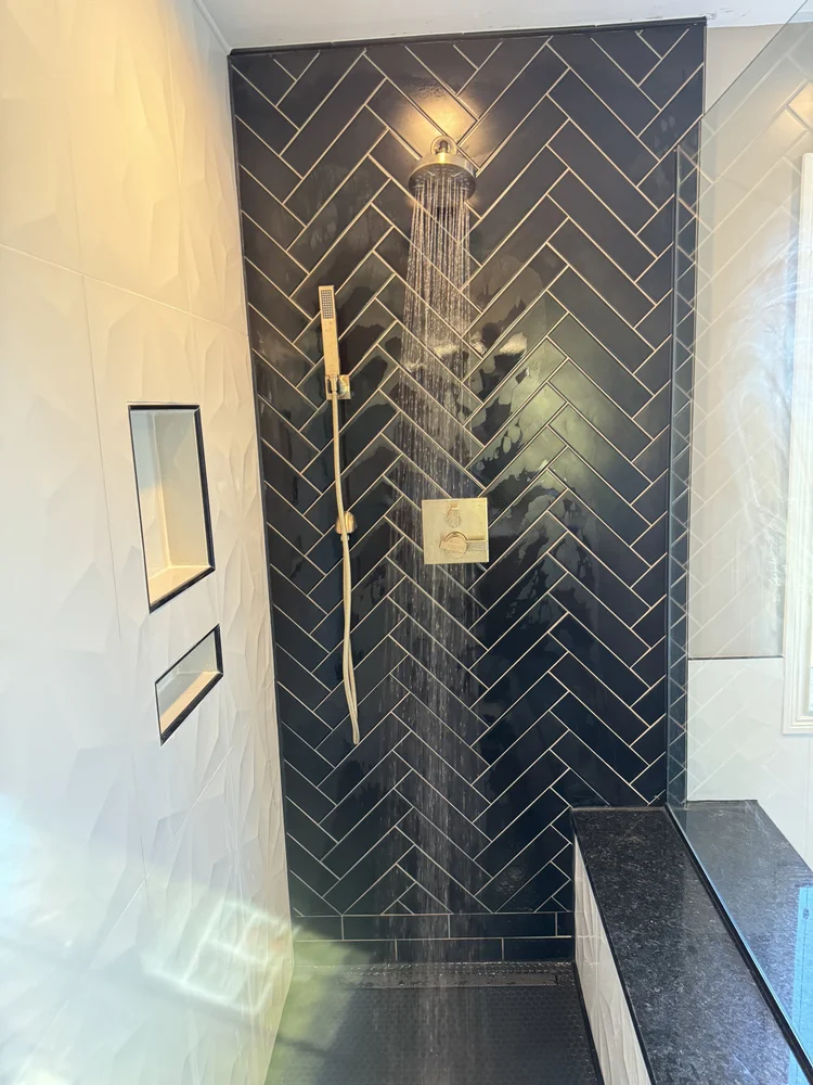 Black herringbone tile shower with bench