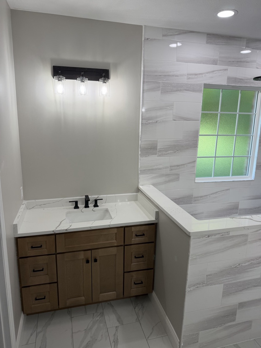 Finished Eaton master bathroom with a wood vanity, marble-look tile and a walk-in shower