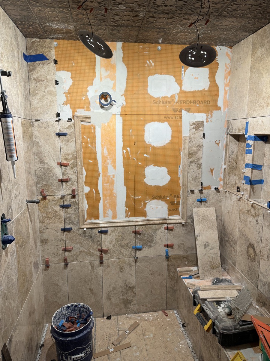 Shower walls covered in orange waterproofing membrane with a framed niche, ready for tile