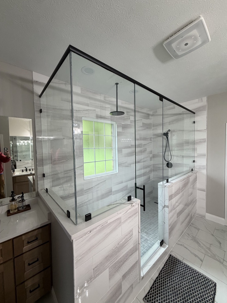 Frameless glass panels with matte black hardware on the walk-in shower