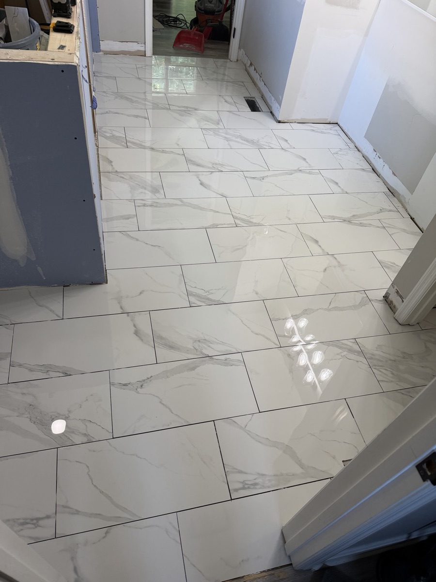 Large-format marble-look porcelain tile floor being installed