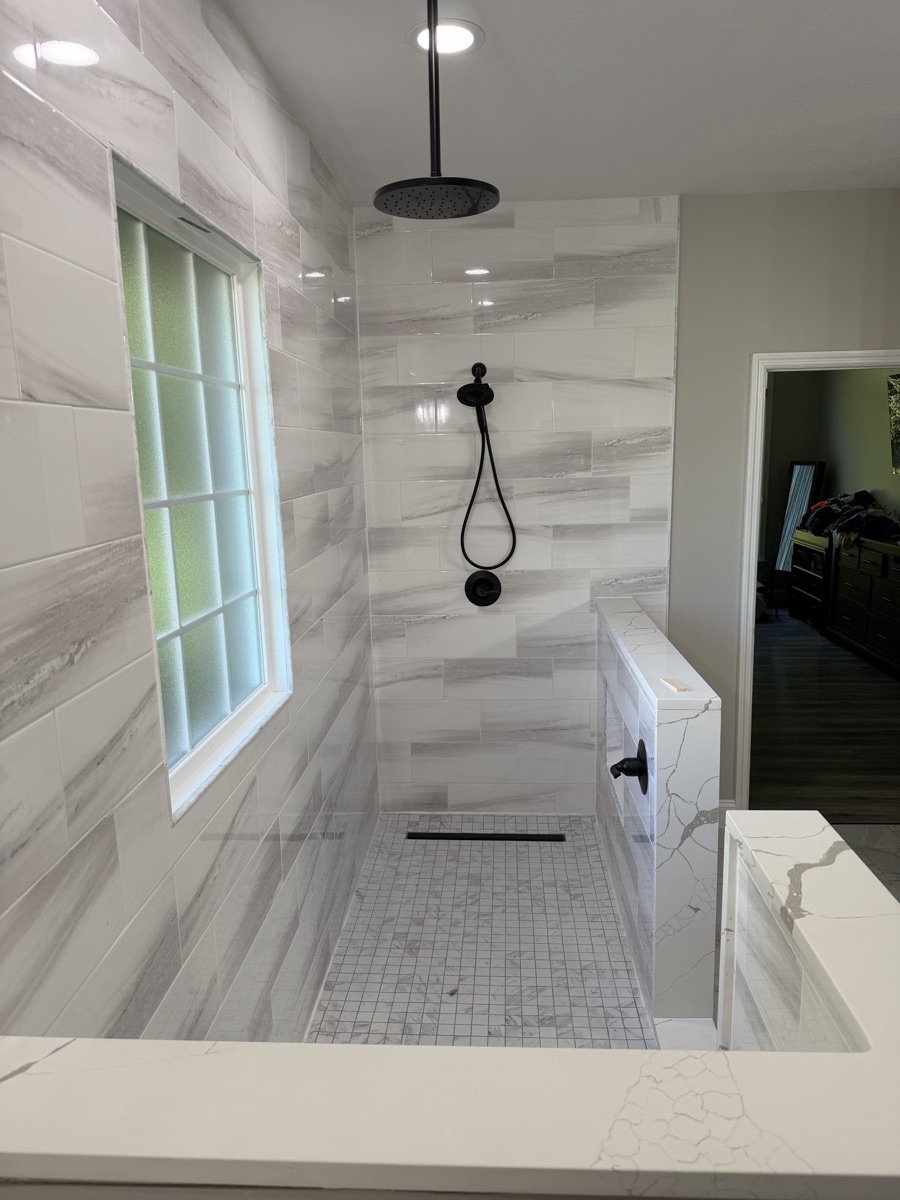 Matte black rainfall shower head, handheld shower and valve in a large-format tile walk-in shower in Eaton, OH