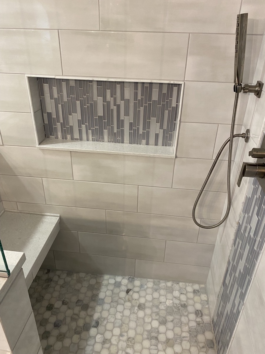 Brushed nickel handheld shower and valve next to a long mosaic tile niche in a Mason, OH shower