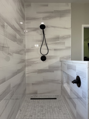 Walk-in shower with matte black handheld and linear drain