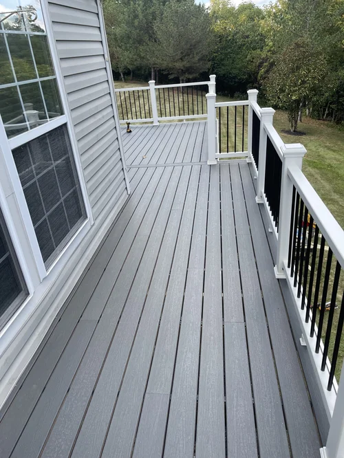Empty gray wooden deck with white and black railing