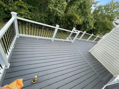 Newly constructed gray wooden deck with white and black railing