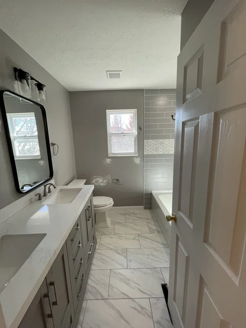 Bathroom with a gray vanity, white countertop, and two sinks