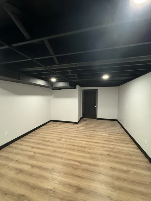 Empty room with black ceiling, white walls, and light wood flooring, Dayton, OH
