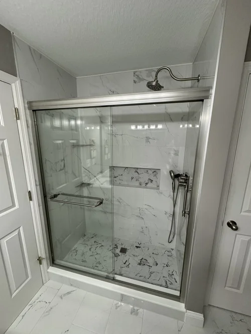 Marble-tiled walk-in shower with a sliding glass door