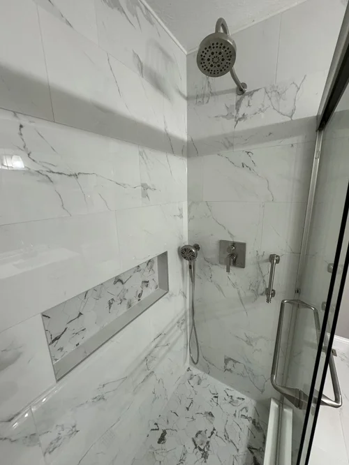White marble tiled walk-in shower with a handheld showerhead