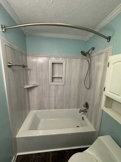 Bathroom with a bathtub, showerhead, blue walls, and a shower curtain rod
