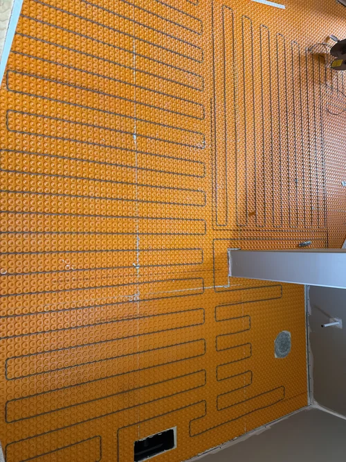 Underfloor heating pipes installed on a bright orange insulation panel in a room under construction, Dayton, OH
