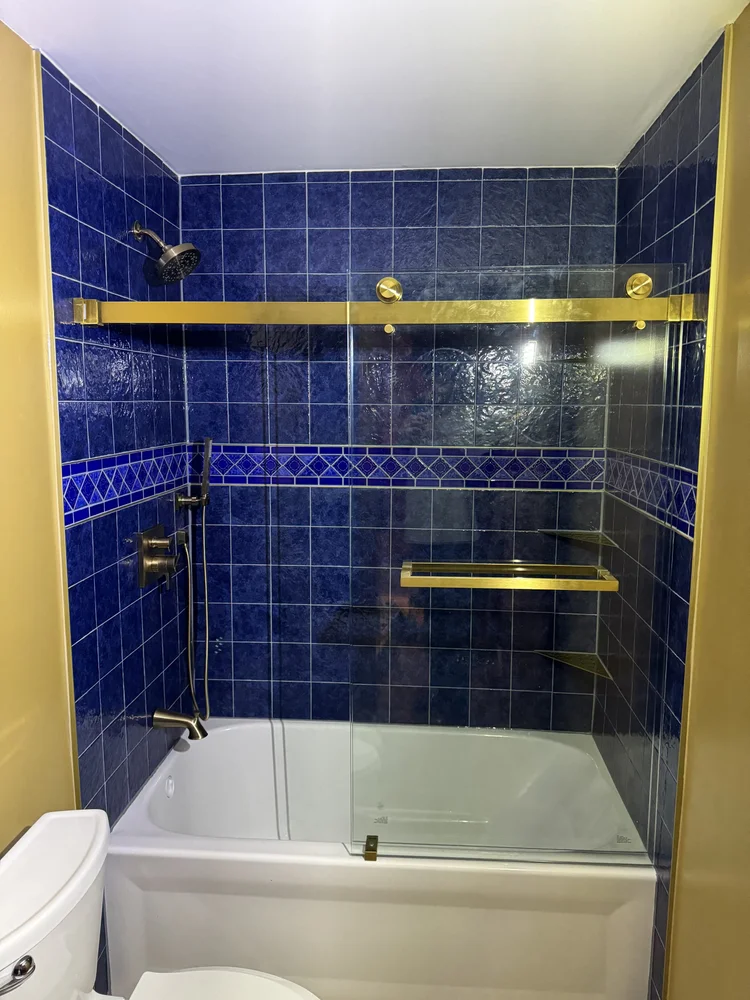 Navy tile shower with brass shelves