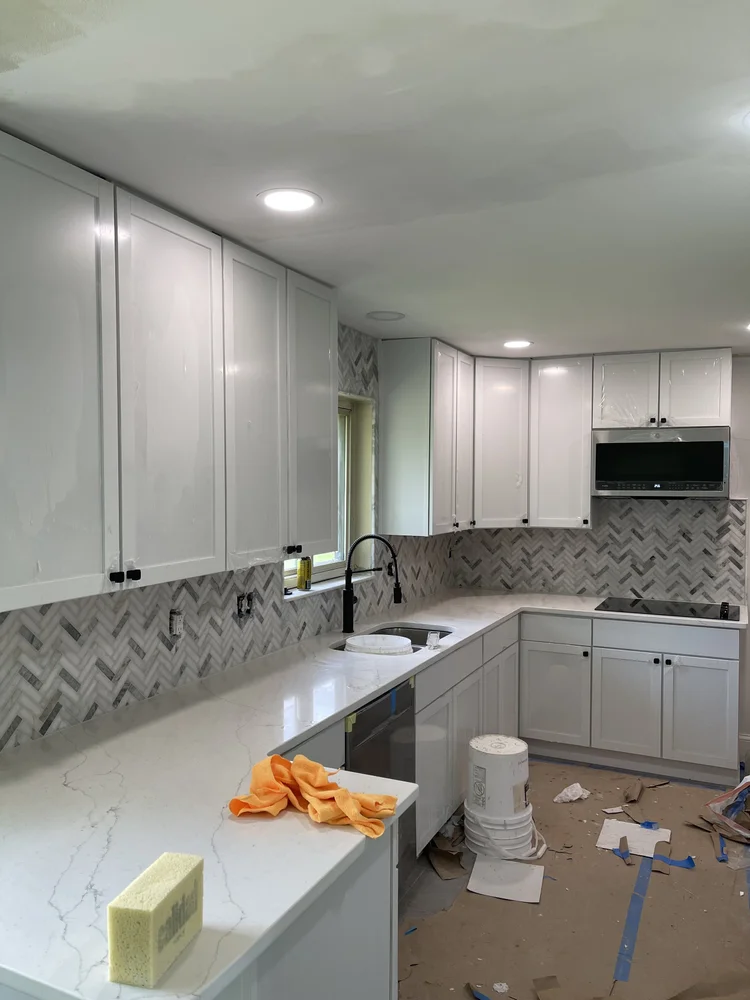 Kitchen with white cabinets and herringbone tile backsplash